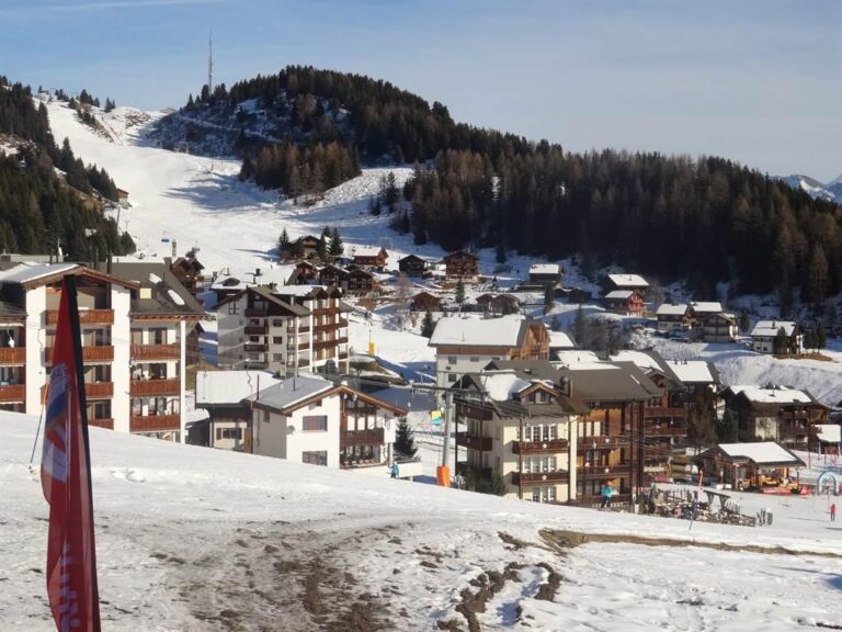 Skipiste mit Dorfblick im Winter